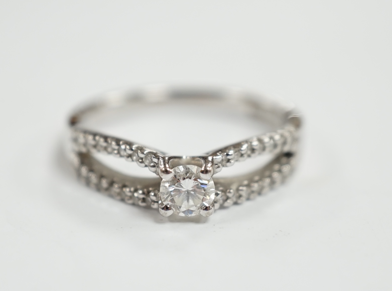A modern 18ct white gold and single stone diamond set ring, with diamond chip set split shoulders, size O, gross weight 4.2 grams.